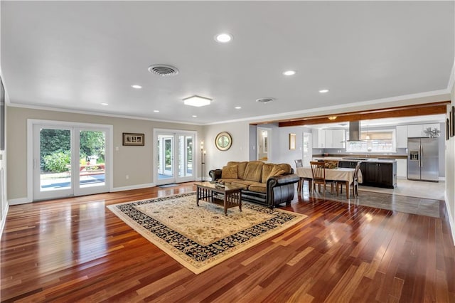 living room featuring wood finished floors, crown molding, french doors, and visible vents