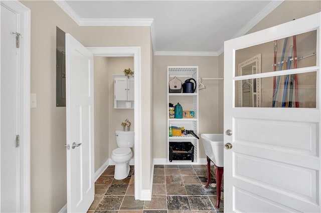 bathroom with stone finish floor, toilet, crown molding, and baseboards