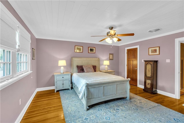 bedroom with ornamental molding, baseboards, and wood finished floors