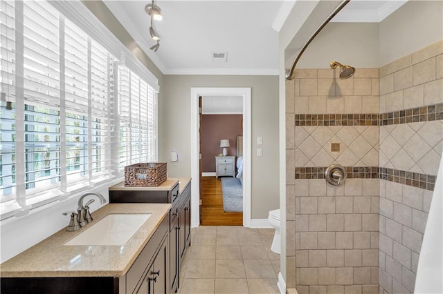 bathroom with vanity, visible vents, tiled shower, ornamental molding, and tile patterned flooring