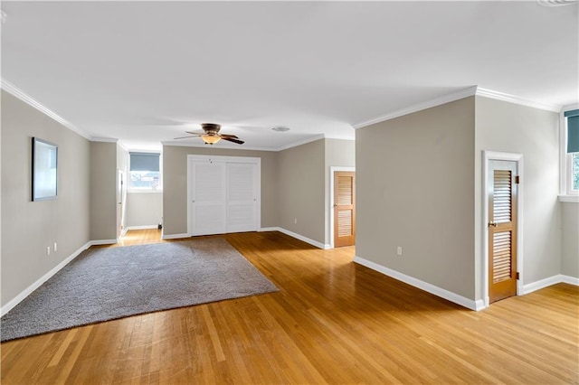 spare room featuring ceiling fan, crown molding, light wood-type flooring, and baseboards