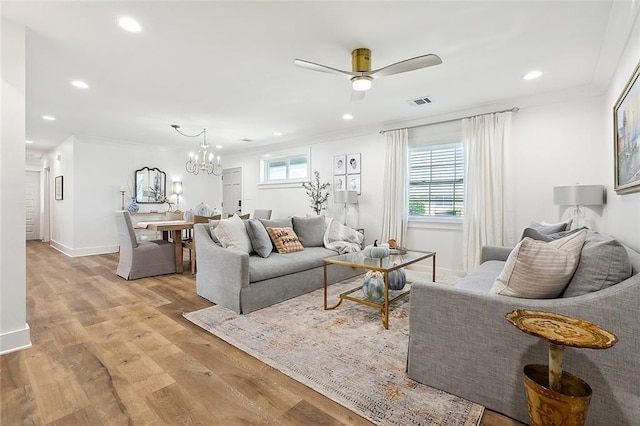 living room featuring ceiling fan with notable chandelier, light wood-type flooring, and ornamental molding