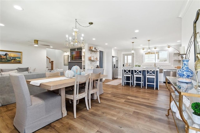 dining area with ceiling fan with notable chandelier and hardwood / wood-style flooring