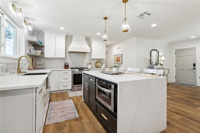 kitchen with white cabinetry, stainless steel range, a kitchen island, and custom exhaust hood