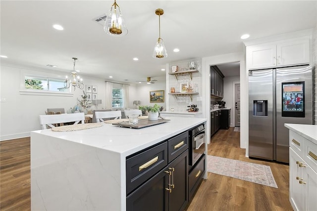 kitchen with stainless steel appliances, wood-type flooring, a center island, white cabinetry, and hanging light fixtures