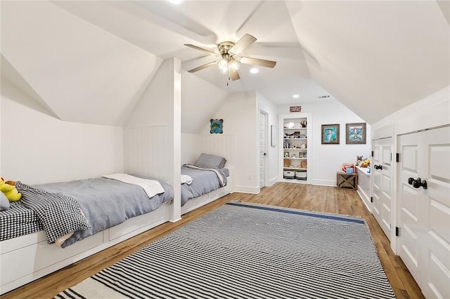 bedroom with ceiling fan, light hardwood / wood-style floors, lofted ceiling, and multiple closets