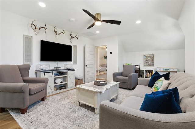 living room featuring ceiling fan, vaulted ceiling, and light hardwood / wood-style flooring