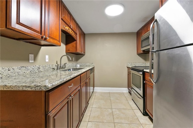 kitchen featuring appliances with stainless steel finishes, light stone countertops, sink, and light tile patterned floors