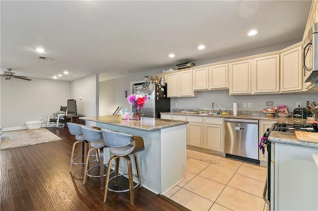 kitchen with cream cabinets, sink, a center island, appliances with stainless steel finishes, and light hardwood / wood-style floors