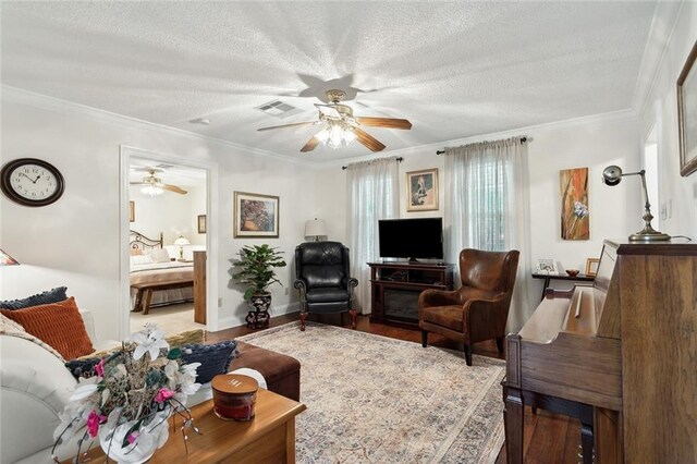 living room featuring crown molding, wood-type flooring, a textured ceiling, and ceiling fan