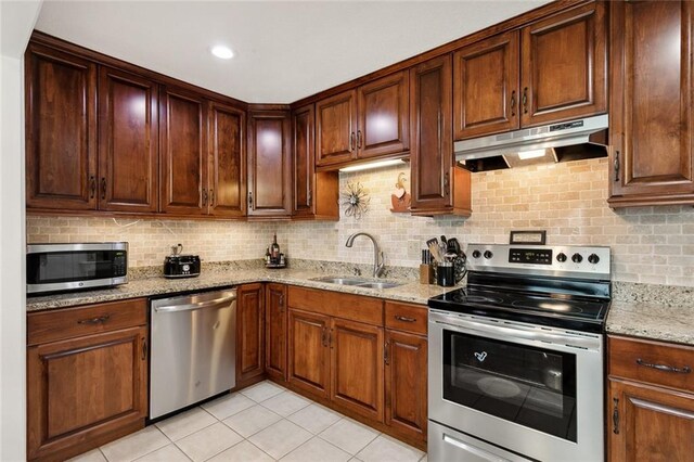 kitchen with tasteful backsplash, stainless steel appliances, sink, and light stone counters