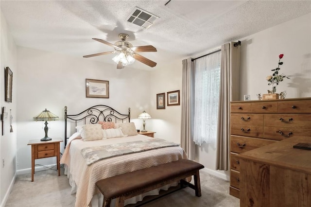 bedroom featuring a textured ceiling, light colored carpet, and ceiling fan