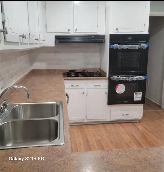 kitchen featuring sink, white cabinetry, tasteful backsplash, light wood-type flooring, and black appliances