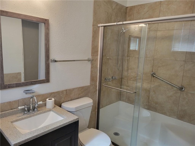 bathroom featuring vanity, a shower with shower door, and toilet