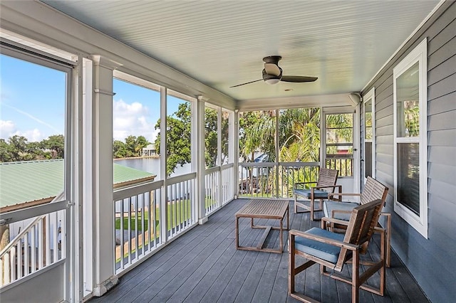 sunroom featuring ceiling fan and a water view