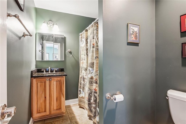 bathroom featuring toilet, tile patterned flooring, baseboards, and vanity