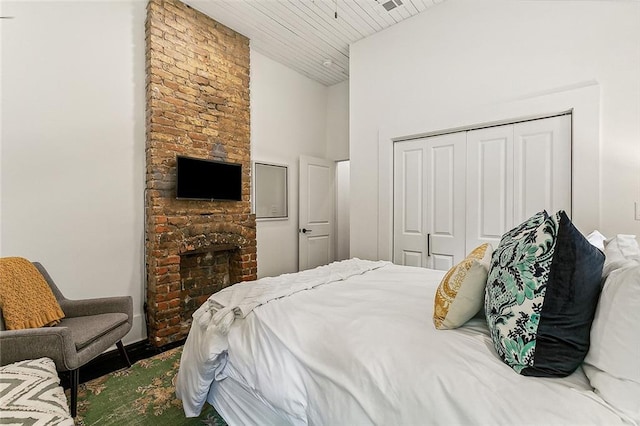 bedroom with a fireplace, a closet, and wooden ceiling