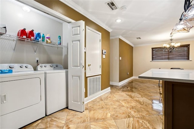 laundry area featuring ornamental molding, washer and dryer, and an inviting chandelier