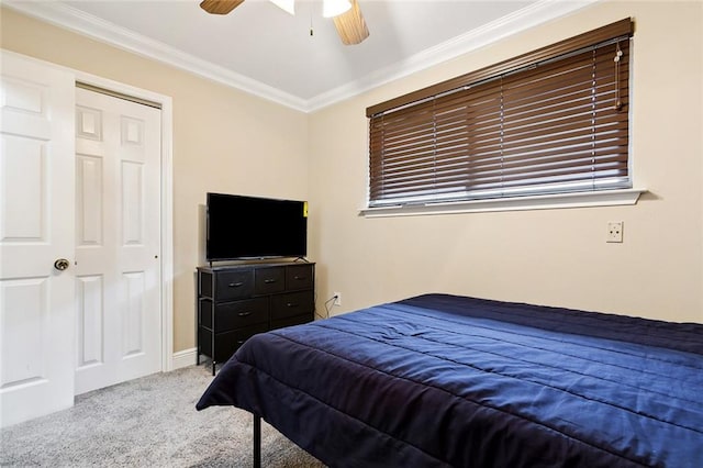 carpeted bedroom with a closet, ceiling fan, and crown molding