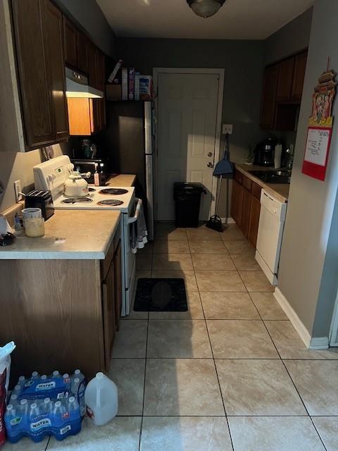 kitchen with white appliances, sink, and light tile patterned floors