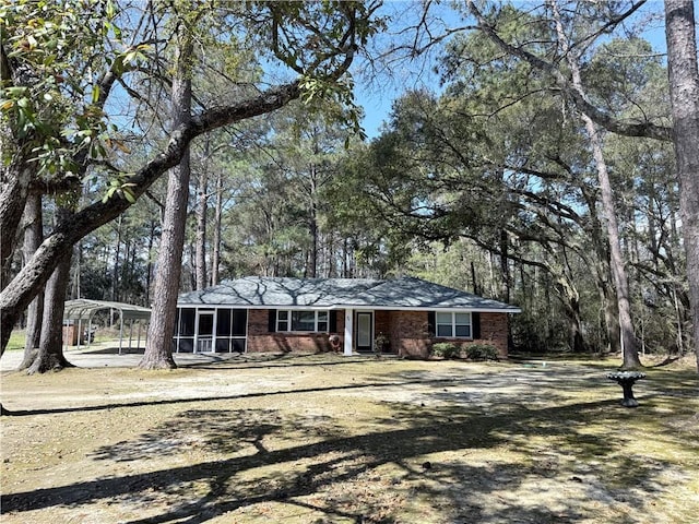 view of front of property featuring brick siding, a detached carport, and a sunroom