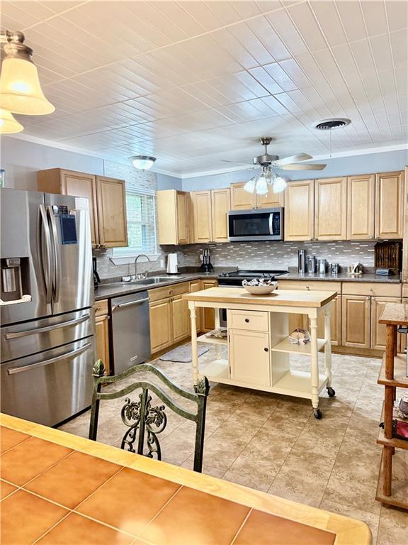 kitchen with stainless steel appliances, backsplash, pendant lighting, light brown cabinetry, and ceiling fan