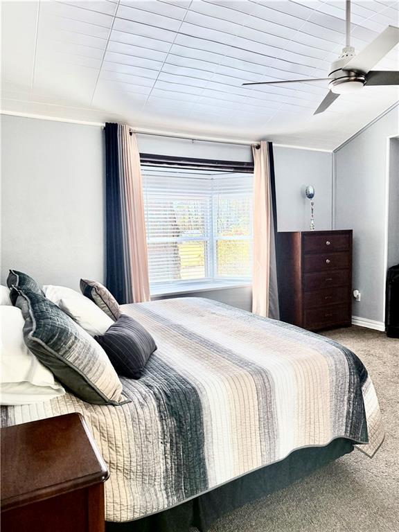 carpeted bedroom with a ceiling fan, baseboards, and ornamental molding