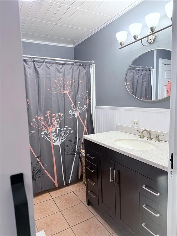 bathroom with wainscoting, crown molding, vanity, and tile patterned floors