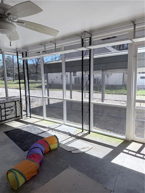 unfurnished sunroom featuring a ceiling fan