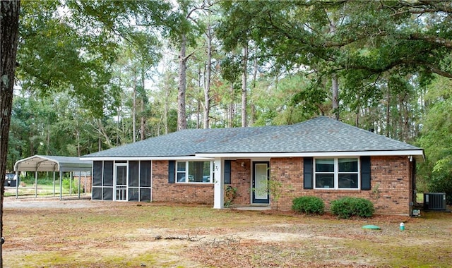 single story home with a front lawn, a carport, cooling unit, a shingled roof, and a sunroom