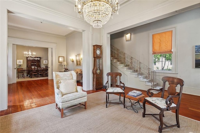 sitting room with wood-type flooring, ornamental molding, and an inviting chandelier