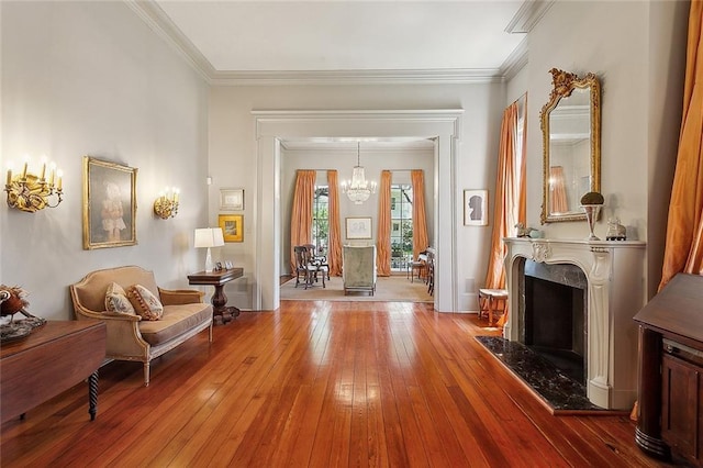 sitting room with crown molding, hardwood / wood-style flooring, a fireplace, and a chandelier