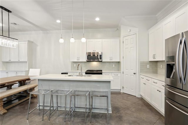 kitchen featuring appliances with stainless steel finishes, white cabinets, a center island with sink, and pendant lighting