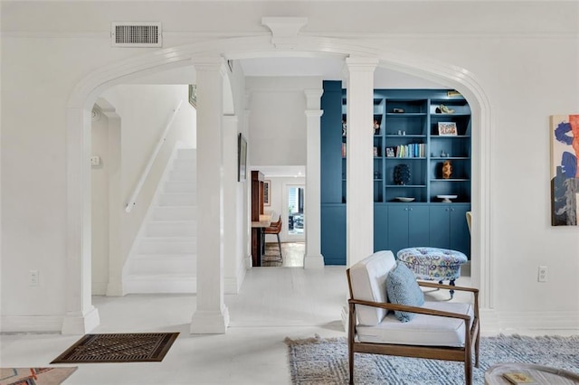 interior space with ornamental molding, built in shelves, and decorative columns