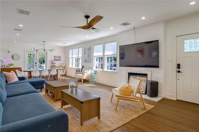 living room with a large fireplace, hardwood / wood-style flooring, a healthy amount of sunlight, and ceiling fan