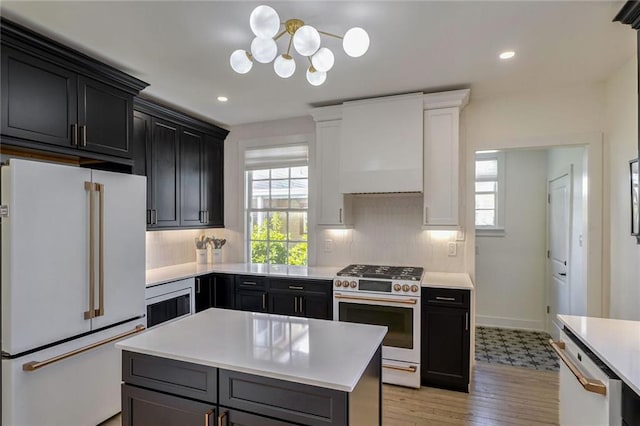 kitchen featuring premium range hood, white cabinetry, light hardwood / wood-style floors, a center island, and white appliances