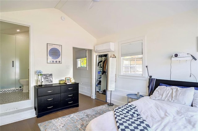 bedroom with lofted ceiling, dark hardwood / wood-style floors, a closet, an AC wall unit, and ensuite bath