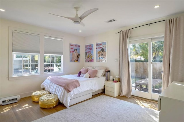 bedroom featuring ceiling fan, access to outside, multiple windows, and hardwood / wood-style floors