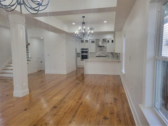 interior space with an inviting chandelier, ornate columns, and light hardwood / wood-style flooring