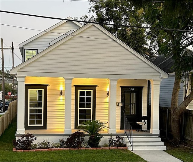 bungalow with covered porch and a front lawn