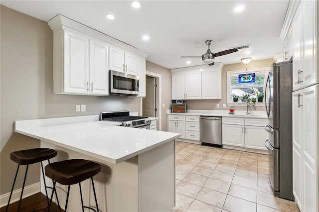 kitchen featuring a kitchen breakfast bar, white cabinetry, kitchen peninsula, and stainless steel appliances