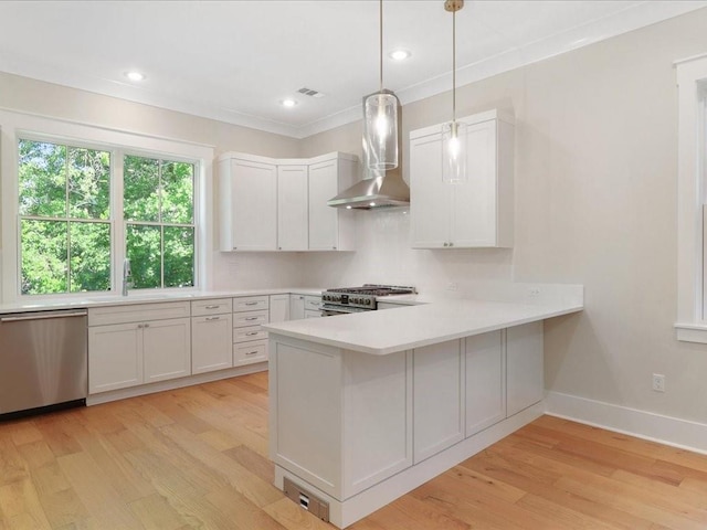 kitchen featuring wall chimney exhaust hood, light wood finished floors, light countertops, and stainless steel appliances