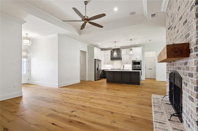 kitchen featuring pendant lighting, custom range hood, an island with sink, and appliances with stainless steel finishes