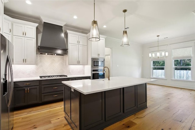 kitchen with appliances with stainless steel finishes, decorative light fixtures, light countertops, premium range hood, and white cabinetry