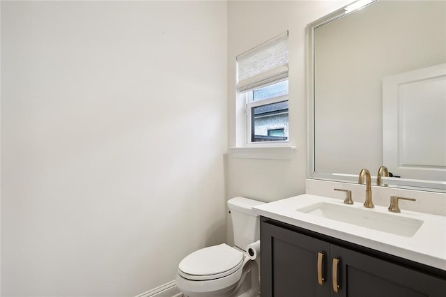 half bath featuring toilet, baseboards, and vanity