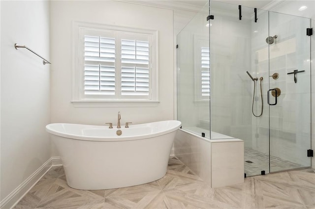 bathroom featuring a stall shower, a freestanding tub, and baseboards