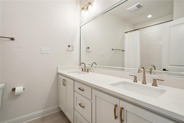 full bath featuring double vanity, a sink, visible vents, and baseboards