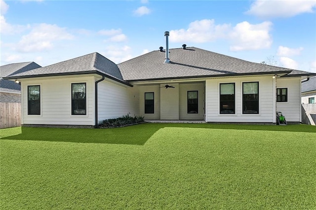 rear view of property featuring a yard, fence, a ceiling fan, and roof with shingles