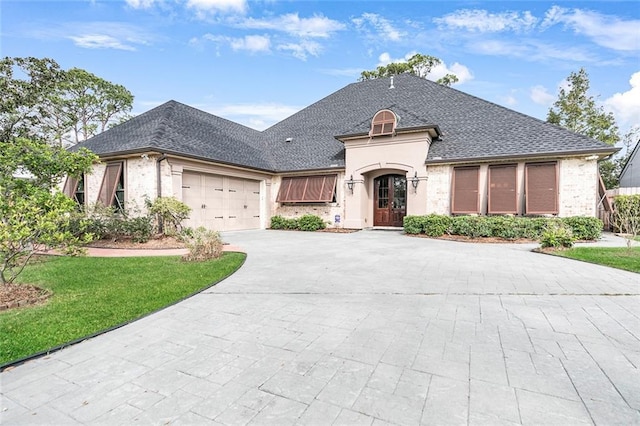 french country style house with a front yard and a garage