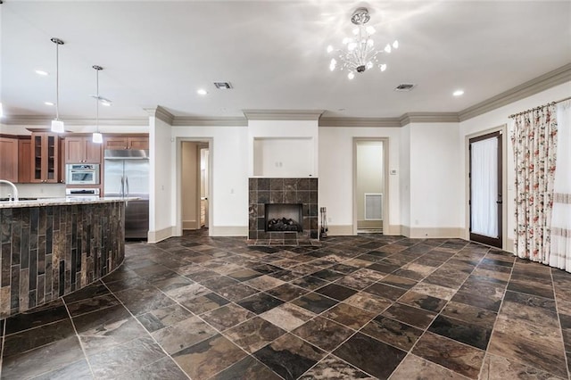 unfurnished living room with a tile fireplace, a chandelier, and ornamental molding